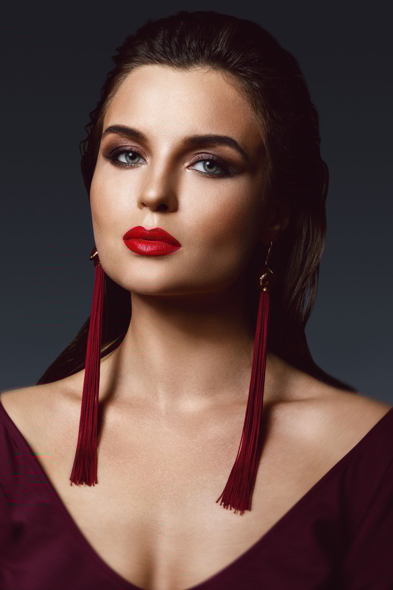 Stunning woman with a beautiful makeup wearing long red earrings
