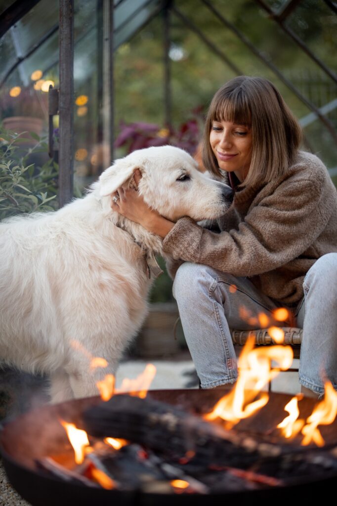 Woman with dog by the fire in garden